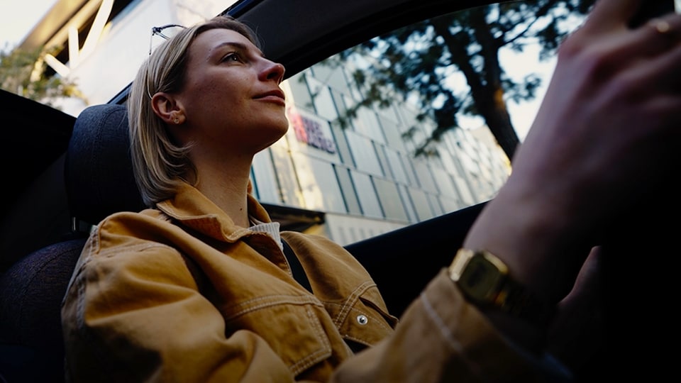 Woman in a yellow jacket driving a car.