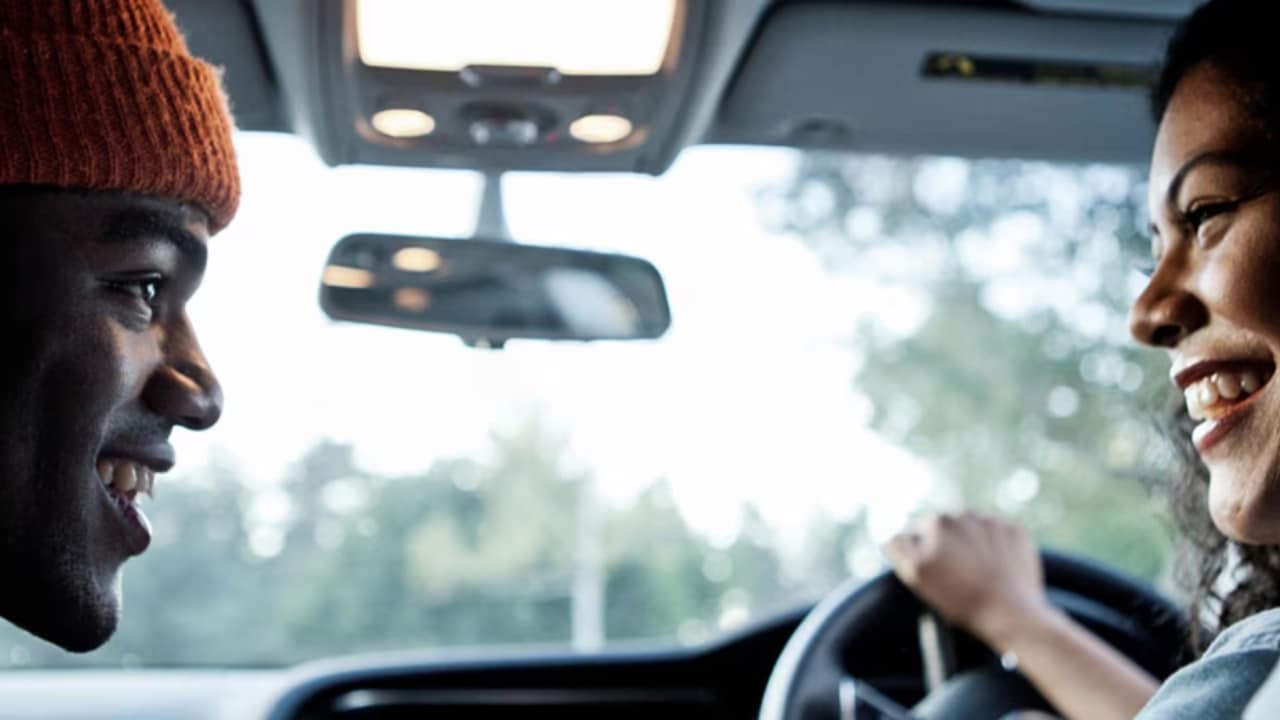 Close up of a man and woman talking in a car.