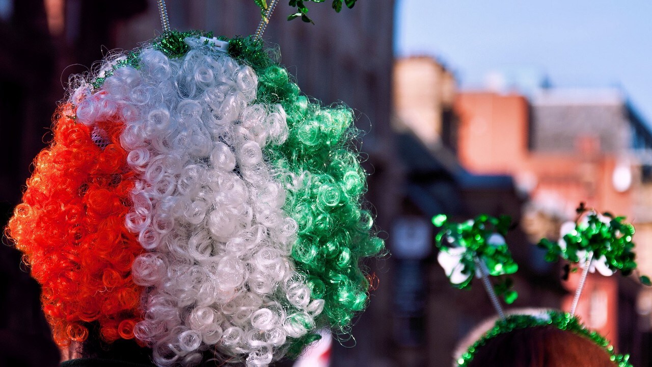 Person in crowd wearing colorful Ireland flag wig at St Patricks Day Parade