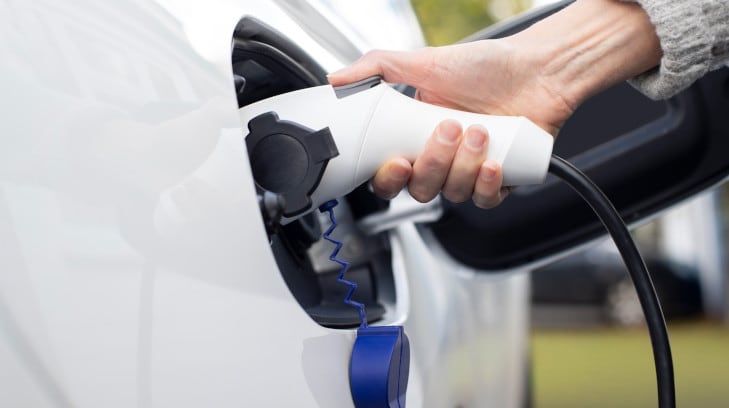 Woman recharging an electric vehicle