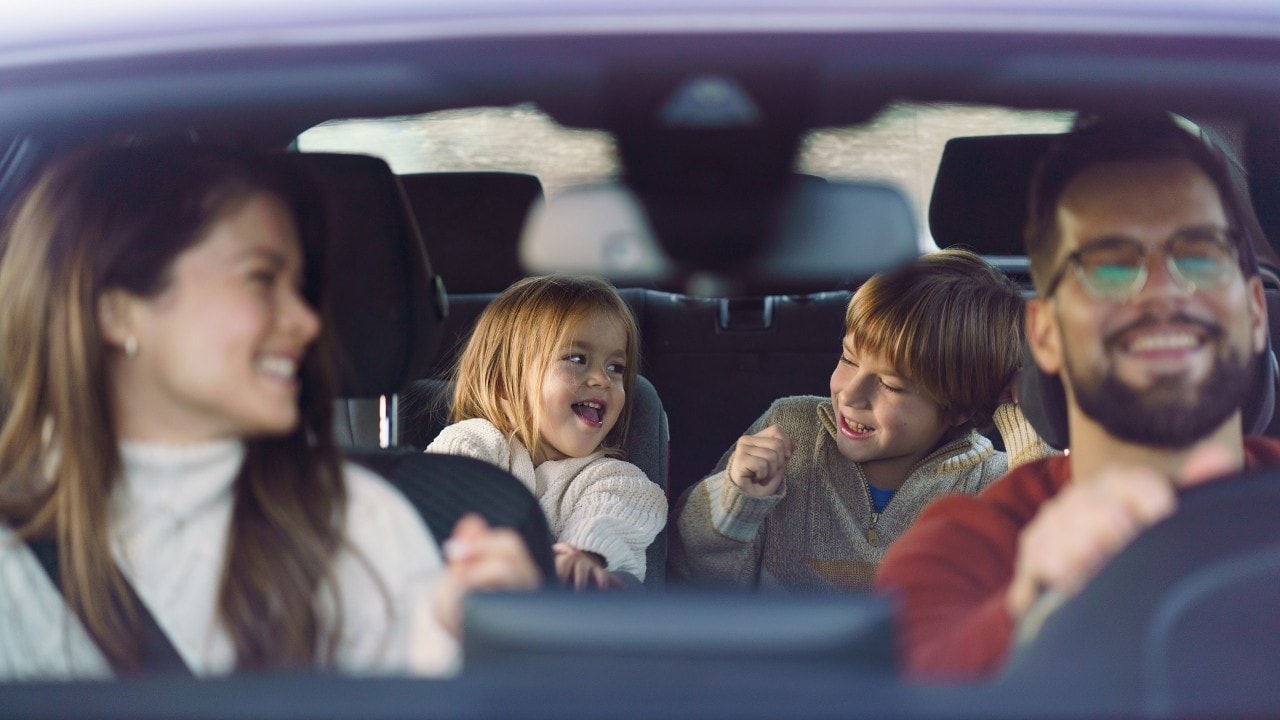 Couple driving with two young children in the back seat