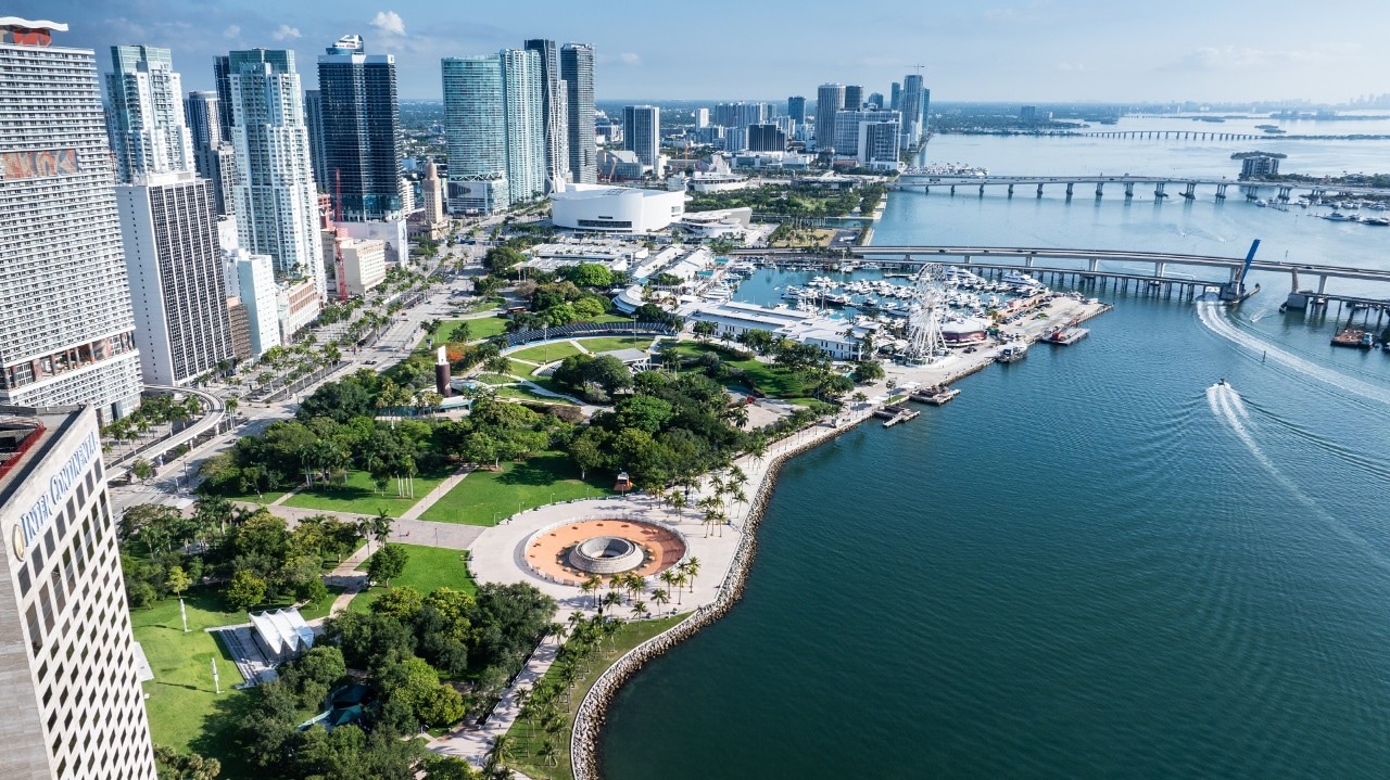 This aerial drone shot of Miami and Biscayne Bay allows us to see into the many aspects of Miami lifestyle and the options for entertainment when travelling.  There is a massive condominium complex, harbors with countless boats and yachts, a beautiful boardwalk, and so much entertainment.  In this photo alone, we see a huge ferris wheel on the boardwalk, as well as jetskis cruising around the bay.  Not to mention the multiple islands connecting to Miami's stunning cityscape full of skyscrapers.
